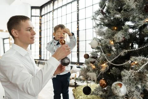 Dad and three year old son sitting smartly dressed by a Christmas tree Stock Photos