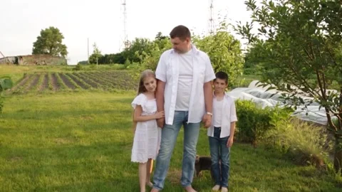 Dad and two children walk together in the green garden near the house. Video stock 140367209