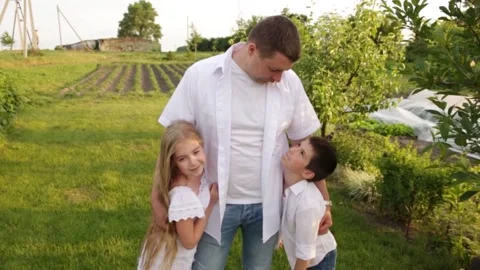Dad and two children walk together in the green garden near the house. Stock Footage 140367280