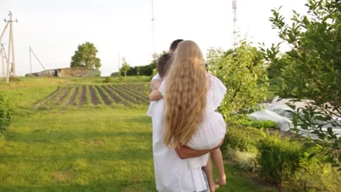 Dad and two children walk together in the green garden near the house. Video stock 140367445
