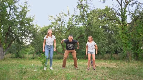 Dad And Two Daughters Are Jumping In The Park Stock Footage 130043856