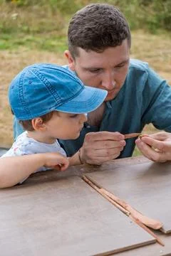 Dad and young son work at the grey table, moulding figures out of red clay Stock Photos