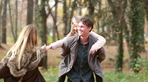 Dad carries daughter on his back while mom spinning around Stock Footage 59554403