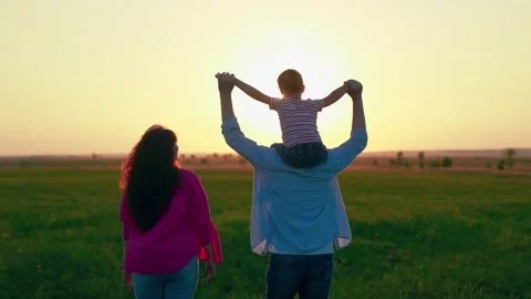 Dad carrying son on shoulders while walking with mom in park sunset. Family Stock Footage 336696271