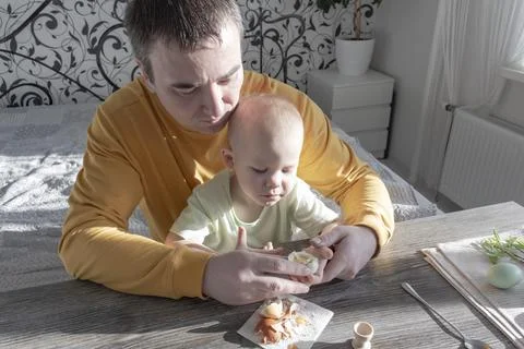 A dad celebrates Easter with his young son. They beat eggs, eat eggs and have Photos