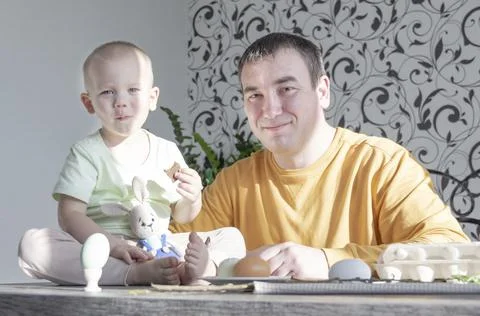 A dad celebrates Easter with his young son. They beat eggs, eat eggs and have Stock Photos
