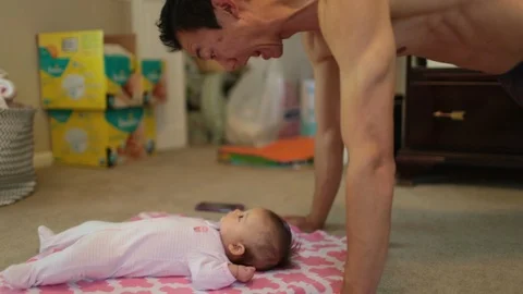 Dad Doing Pushups and Playing with Baby on Floor Stock Footage 90265820
