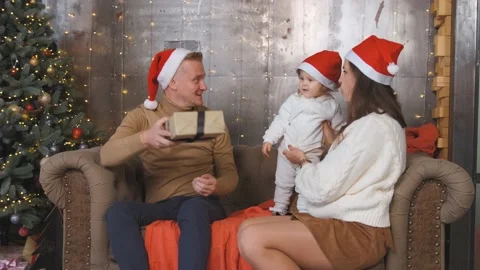 Dad gives a gift from under the tree to his little daughter. Family next to Stock Footage 142572201