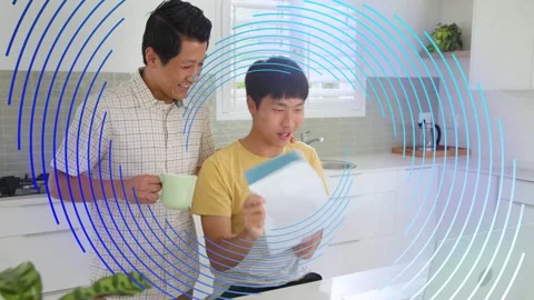 Dad giving teal-header doc to son reviewing on silver laptop for education, blue Stock Footage 332732534