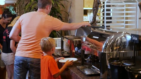 Dad help kids go through hotel breakfast buffet line Stock Footage 94236204