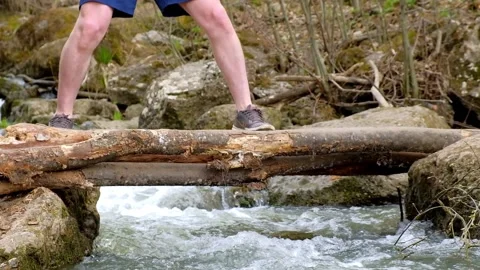 Dad helps a child cross a makeshift bridge over a river Stock Footage 153833662