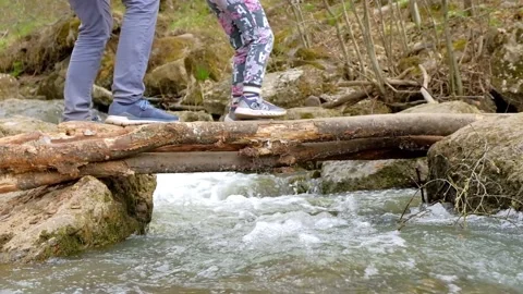 Dad helps a child cross a makeshift bridge over a river Stock Footage 153833670