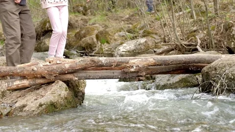 Dad helps a child cross a makeshift bridge over a river Stock Footage 153833671