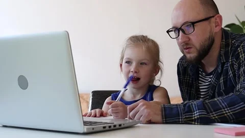 Dad helps daughter to do homework from internet. Video stock 244007984