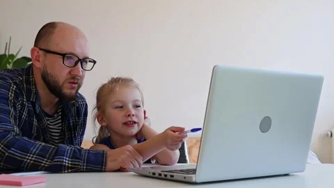 Dad helps daughter to do homework from internet. Stock Footage 244007991