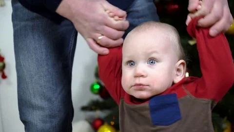 Dad holding baby's hands helping him. Stock Footage 72023674