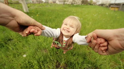 Dad holding hands of his dauther while flailing her on the garden Stock Footage 64540388
