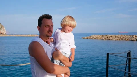 Dad holds his son in his arms and shows him something with a finger in white Stock Footage 200784558