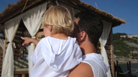 Dad holds his son in his arms and shows him something with a finger in white Stock Footage 234470308