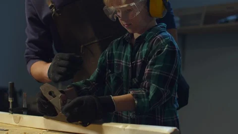 Dad instructs his little son how to work at a workbench Stock Footage 128183113