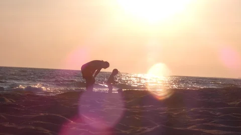 Dad looking at toddler son in sand, having fun at sunset, multiethnic father Stock Footage 129663977
