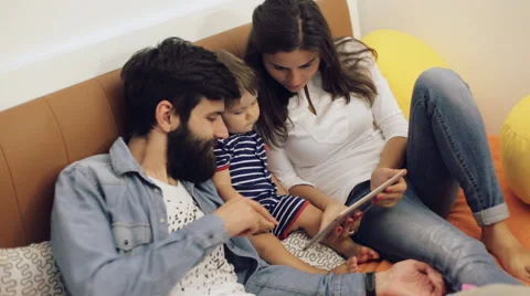 Dad, mom and their young son having fun by playing together on a tablet, they Stock Footage 64523182