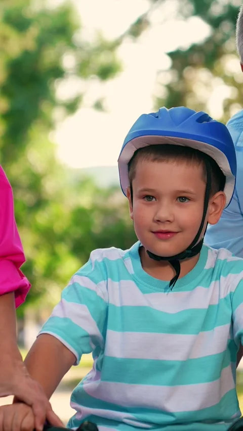 Dad mom teaching son ride bike in park. Kid cyclist with parents in city park Stock Footage 336622062