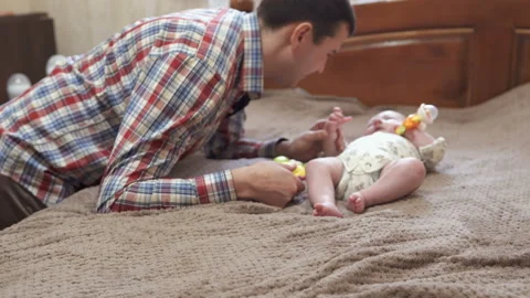 Dad is playing with the baby on the bed Stock Footage 104855085