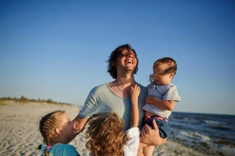 Dad is playing on the beach with three children. Stock Photos