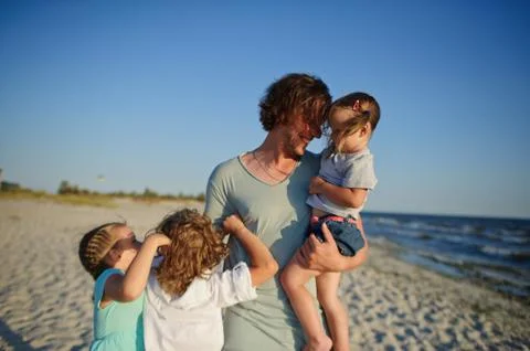Dad is playing on the beach with three children. Stock Photos
