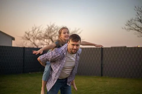 Dad playing with his daughter in the backyard of the house Stock Photos