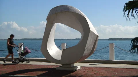Dad pushes baby cart while walking by Brickell Bay Drive's sculpture in Miami Video stock 61242386