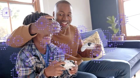 Dad reaching over boy during gaming, purple chip overlay on pads, teasing Stock Footage 333733584