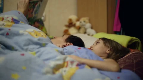 Dad reading the book to daughter bedtime Stock Footage 60350730