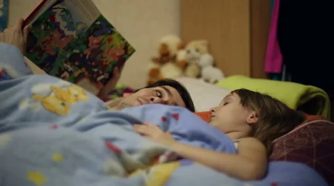 Dad reading the book to daughter bedtime Stock Footage 60350906