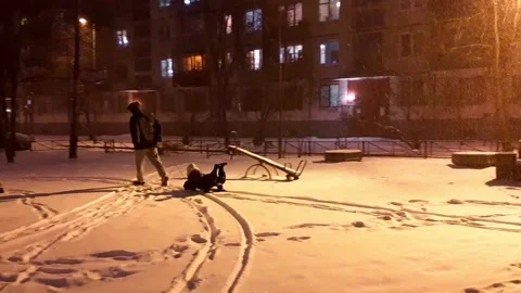 Dad rides a child on a sled. Winter evening. Children's playground. Stock Footage 168536732
