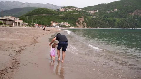 Dad runs along the sandy beach holding the hands of a little girl Stock Footage 284069358