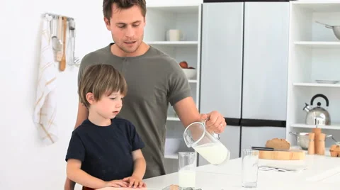 A dad serving a glass of milk to his son Stock Footage