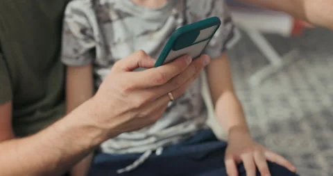 A dad shows son how to operate the washing machine from the mobile app. He turns 스톡 동영상 200848125