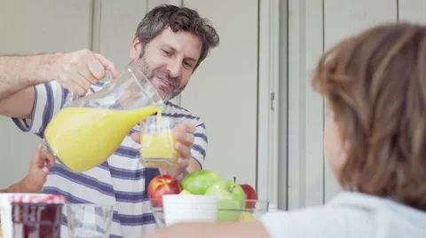Dad sit down and serve orange juice for his son Stock Footage 65170588