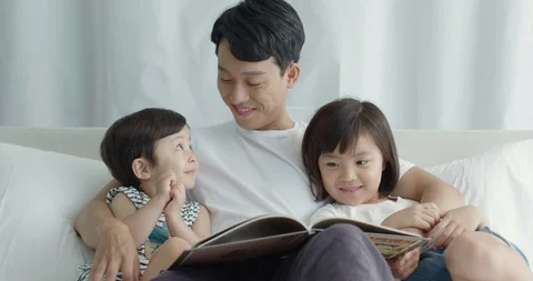 Dad is sitting in bed and playing with his little son and daughter Stock Footage 100937000