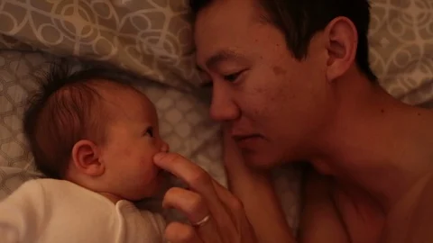 Dad Snuggles with Baby in Bed 動画素材 90257341