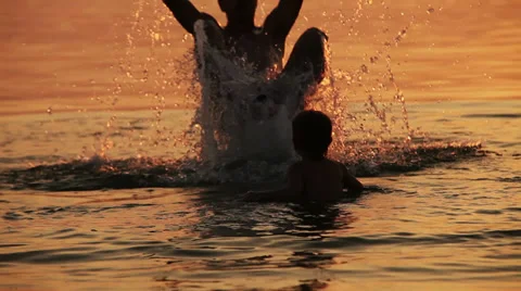 Dad with son fooling around in sunset waves Stock Footage 30924867