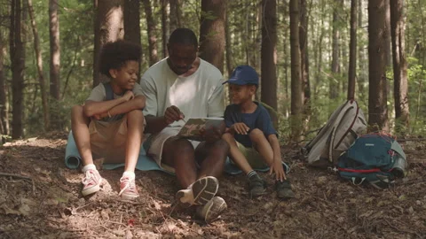 Dad with Sons Looking at Map while Camping Stock Footage 159443273