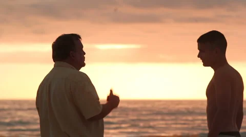 Dad takes time to talk to son at beach Stock Footage 1003253
