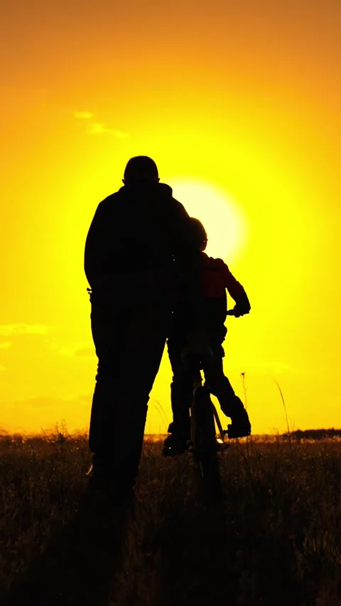 Dad teaches her child son to ride bike, nature. Family games. Father teaches her Stock Footage 303650751