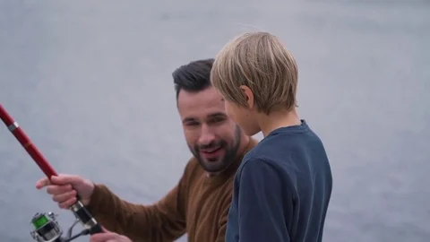 Dad teaches his son how to handle a fishing rod Stock Footage 80842485