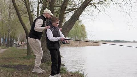Dad teaches his son how to catch predatory fish in the river. Stock Footage 309921061