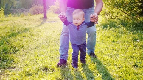 Dad teaches his son to walk. Little boy makes his first steps. Slow motion Stock Footage 75467279