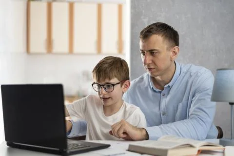 Dad teaches his son to work with computer program. Dad helps his son do homew Fotos de archivo